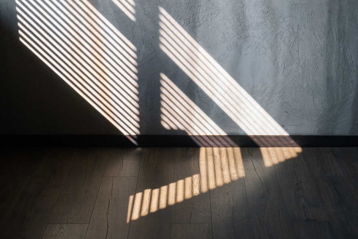 Light and shadow from the window. Thin lines of light on the wall and floor. Light and shadow from the window. Thin lines of light on the wall and floor. The texture of the plaster. Shadow from the blinds.